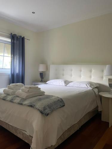 a white bedroom with a large white bed with pillows at Camelias in Guimarães