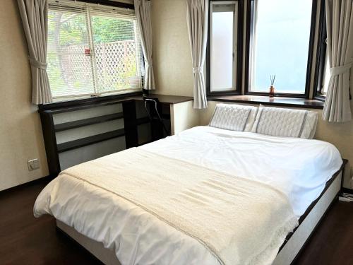 a bedroom with a white bed with two windows at 禮 -Rei House- in Muromimachi