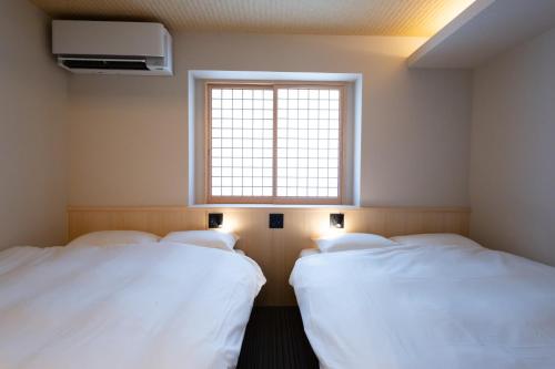 two beds in a room with a window at 別府 夕凪 in Beppu