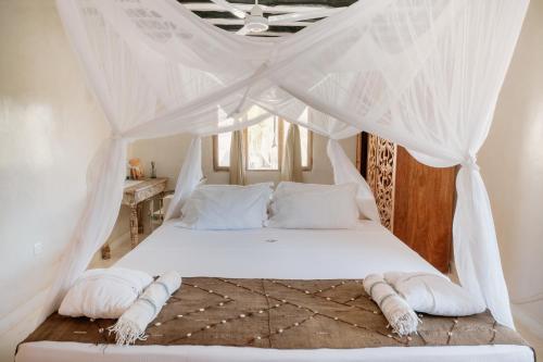 a bedroom with a white bed with a canopy at Alawi Home in Watamu