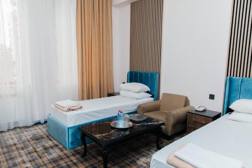 a hotel room with two beds and a chair and a table at Ganja Hotel in Ganja