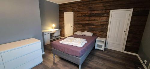 a bedroom with a bed and a wooden wall at The Yellow House in Boden