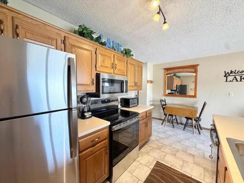 a kitchen with a stainless steel refrigerator and wooden cabinets at LOTO fun at 21 Lakeview Condo in Osage Beach