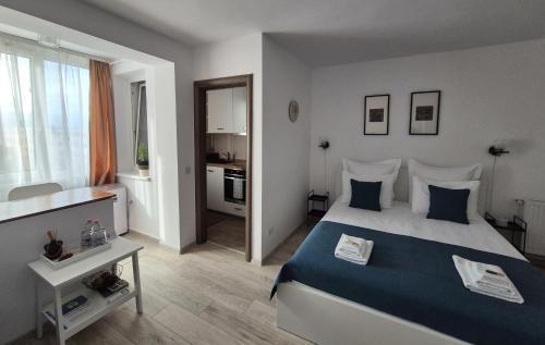 a bedroom with a blue and white bed and a kitchen at ZARA STUDIO BRASOV in Braşov