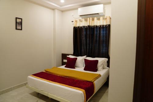 a bedroom with a bed with red pillows at Hotel Vijaya Comfort in Hyderabad