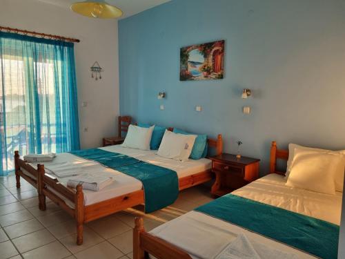 two beds in a room with blue walls at Calypso Studios in Amoudi