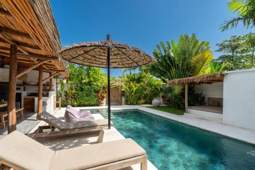 a villa with a swimming pool and an umbrella at Villa Ruta I - Sumptuous 2BR Luxury Villa next to Luna Beach Club and Nyanyi Beach in Tanah Lot