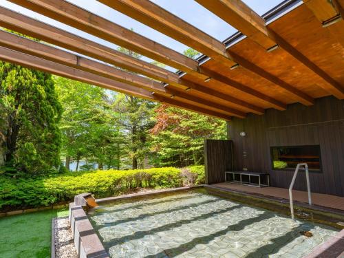 a patio with a pool and a wooden pergola at Tateshina Lake Resort in Tateshina