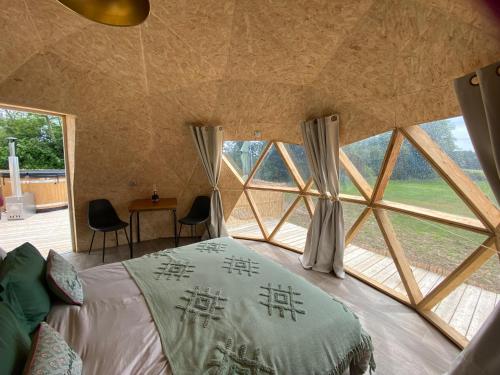 a bedroom with a bed and a large window at le dôme avec bain nordique in Amfroipret