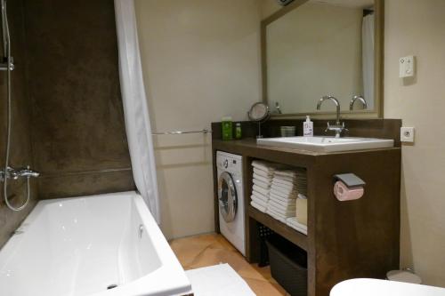 a bathroom with a tub and a sink and a washing machine at Domaine de Villedese in Montlaur
