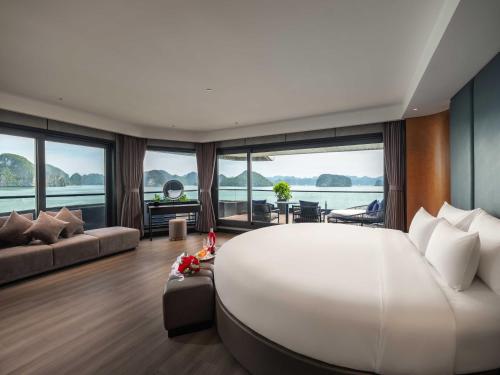 a large white bed in a room with windows at Victorious Cruise Ha Long Bay in Ha Long