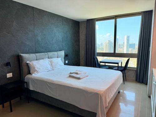 a hotel room with a bed and a large window at Sea Breeze Studios in Netanya