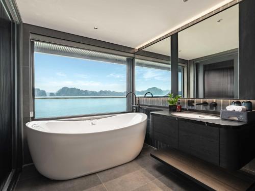 a bathroom with a large tub and a large window at Victorious Cruise Ha Long Bay in Ha Long