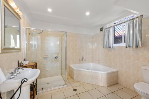 a bathroom with a tub and a shower and a sink at Charlesworth On The Park in Glen Innes