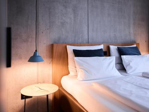 a bedroom with a bed with white pillows and a table at Sternen Bohlingen Aparthotel in Bohlingen