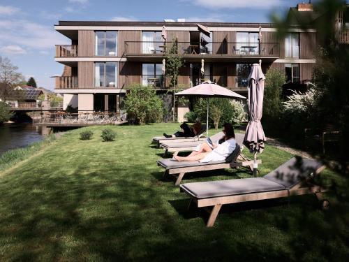 a group of people sitting on lounge chairs in front of a building at Sternen Bohlingen Aparthotel in Bohlingen