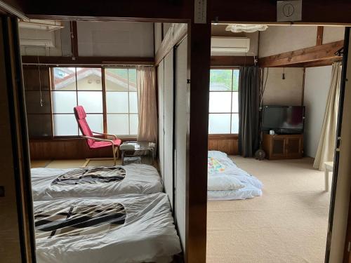ein Schlafzimmer mit einem Bett und einem Stuhl in einem Zimmer in der Unterkunft Nabiki in Hongu