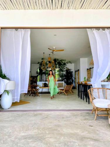 a woman in a green dress walking through a living room at Tides Signature Koh Chang in Ko Chang
