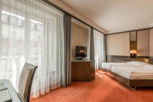 a hotel room with a bed and a large window at Hotel Monopol Luzern in Lucerne