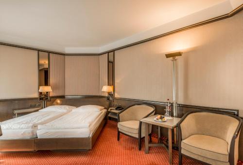 a hotel room with a bed and a table and chairs at Hotel Monopol Luzern in Lucerne