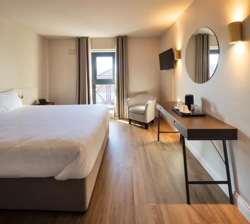 a hotel room with a bed and a desk at The Village Hotel Douglas in Cork