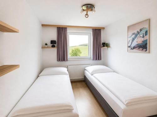 two beds in a small room with a window at Apartment Ledermoos - Ski, Langlauf & Wandern in Mauterndorf in Mauterndorf