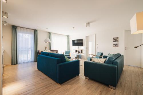 a living room with two blue couches and a television at Am Park 15 in Prerow