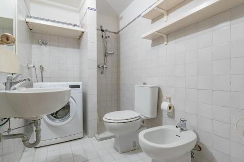 a white bathroom with a toilet and a sink at Villa Thalèa Fetovaia in Fetovaia