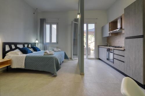a bedroom with a bed with blue pillows and a kitchen at Agrù - Salento Garden Stay in Cavallino di Lecce