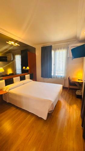 a bedroom with a large white bed and a desk at U-Hotel Boutique Oria in Tolosa