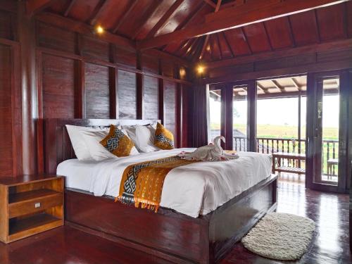 a bedroom with a large bed in a room with windows at Merlyn Meadows Retreat in Munduk