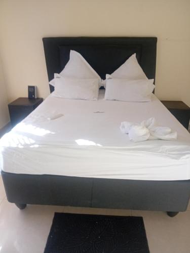 a large bed with white sheets and pillows at Otam-Check Guest House in Ondangwa