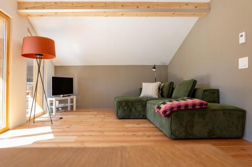 a living room with a green couch and a television at Ferienwohnung Loipenblick in Obergesteln