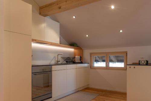 a kitchen with white cabinets and a window at Ferienwohnung Loipenblick in Obergesteln