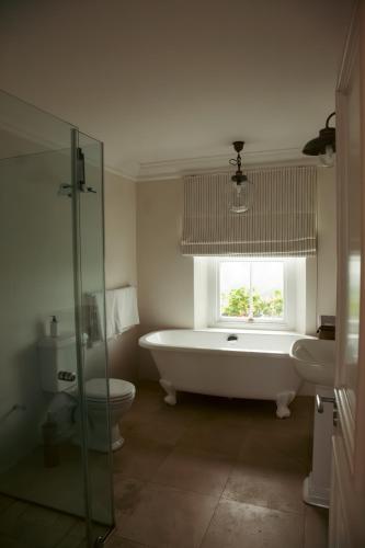 a bathroom with a tub and a toilet and a window at Hawksmoor House in Stellenbosch