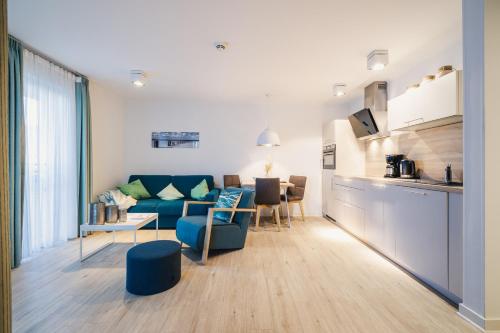 a living room with a blue couch and a kitchen at Am Park 3 in Prerow