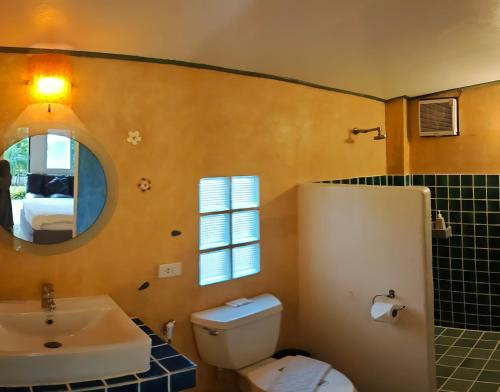 a bathroom with a toilet and a sink and a mirror at KuadKhonThoe Pai Cottage in Pai