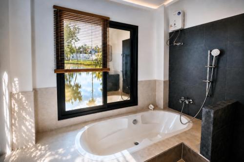a bath tub in a bathroom with a window at Kenikar Raintree Resort Chumphon in Chumphon