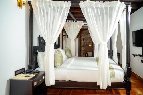 a bedroom with a canopy bed with white curtains at SVS Arena in Kizhake Chālakudi