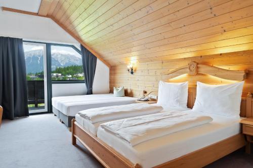 a bedroom with two beds and a large window at Hotel Gruberhof Innsbruck Igls B&B in Innsbruck