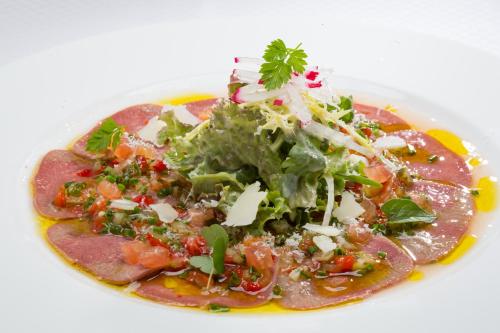 a plate of food with a salad and meat at Der Erlhof Restaurant & Landhotel in Zell am See