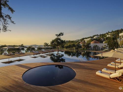 a pool with lounge chairs and a wooden deck at Rixos Premium Bodrum in Torba