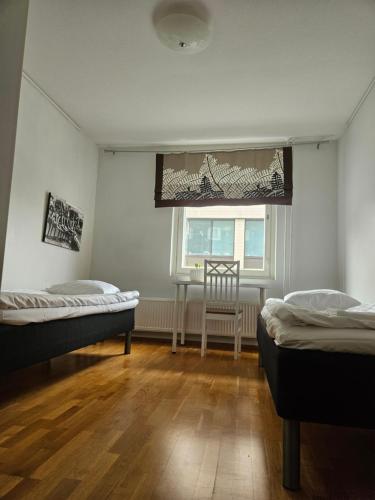 a room with two beds and a window and a chair at Apartment Asemakatu 20 in Kuopio