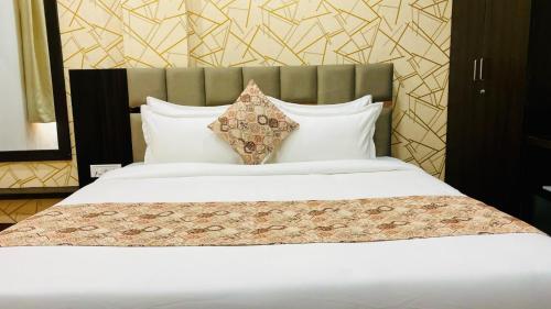 a large bed with white sheets and pillows at Hotel Rove Inn in Indore