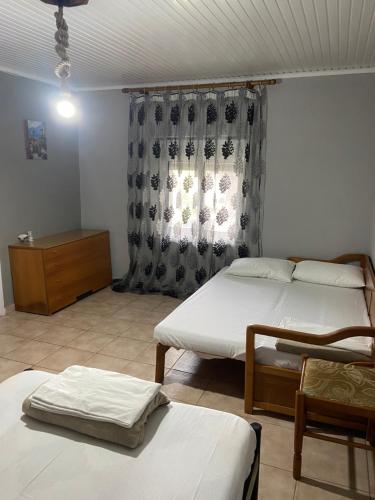 a room with two beds and a dresser and a window at Papadopoulos House in Kavála