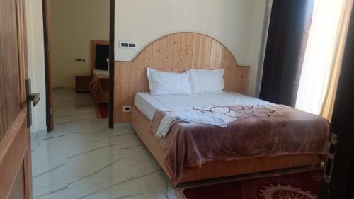 a bed with a wooden headboard in a room at Hotel Turi & Punjabi Restaurant in Rewalsar