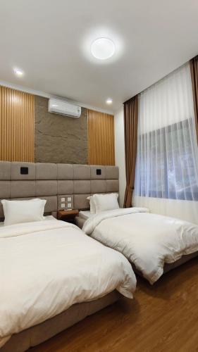 a bedroom with two beds and a window at Villa Dalia Puncak EE11-24 in Cikujang