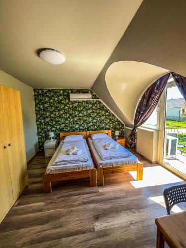 a bedroom with two beds and a window at Zöldház Panzió in Gyenesdiás