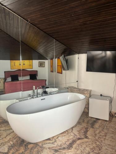 a large white bath tub in a room with a bed at Canada Castle in Eforie Nord