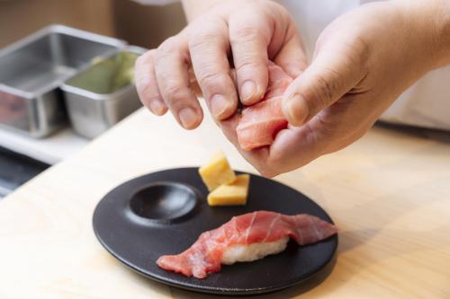 a person holding a piece of food on a plate at Richmond Hotel Sapporo Odori in Sapporo